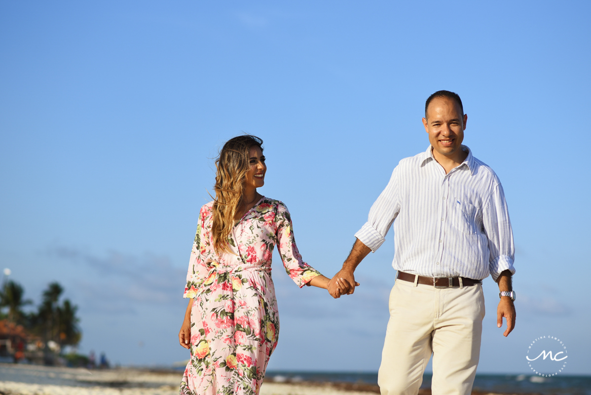 Couple holds hands while walking on beach. Playacar engagement session by Martina Campolo Photography