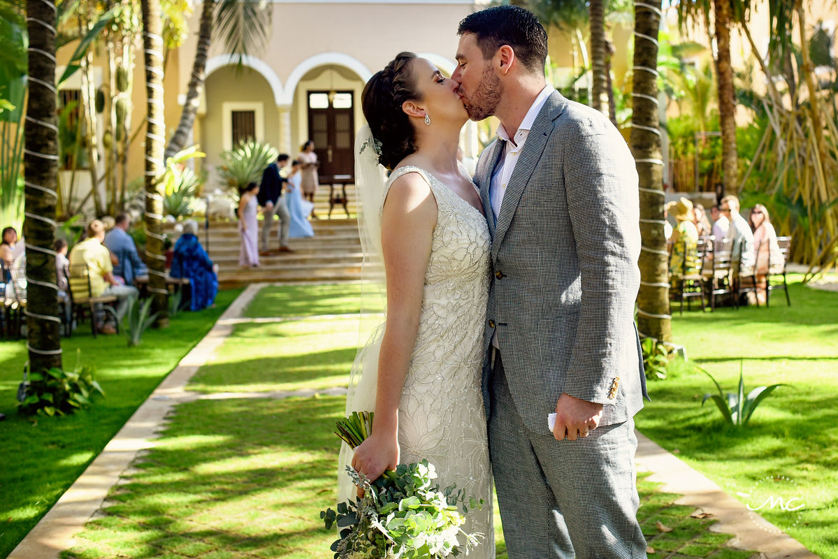 Newlyweds kiss at garden wedding. Hacienda del Mar, Puerto Aventuras, Mexico. Martina Campolo Photography