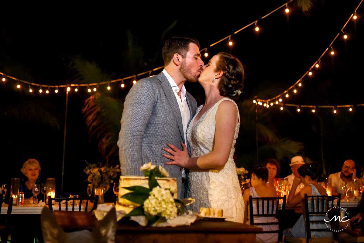 Bride and groom kiss next to wedding cake. Hacienda del Mar wedding in Mexico by Martina Campolo Photography